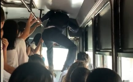 Joven camina sobre los asientos para poder descender de un microbús saturado